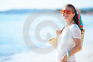 Smiling modern woman on ocean shore looking into distance