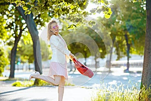 smiling modern woman in pink dress and white jacket in city