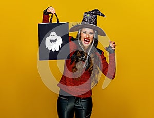 Smiling modern woman showing shopping bag and frightening