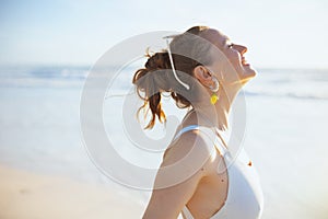 Smiling modern woman in white beachwear at beach relaxing