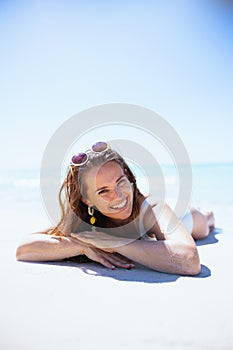 Smiling modern 40 years old woman laying at beach