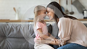 Smiling mom and daughter cuddle playing at home