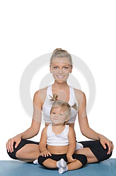 Smiling mom and daughter doing yoga on mat