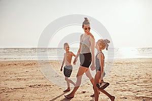 Smiling Mom and her kids walking along a sandy beach
