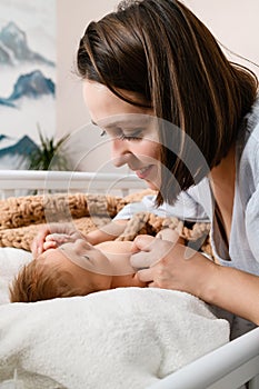 Smiling mom hold hands of newborn baby