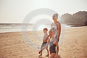 Smiling Mom and two children walking along a sandy beach