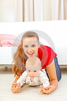 Smiling mommy and adorable baby playing on floor