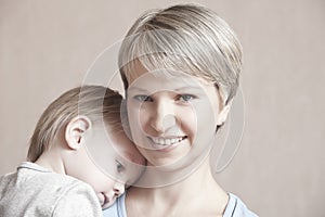 Smiling Mother With Baby Boy Leaning On Her Shoulders