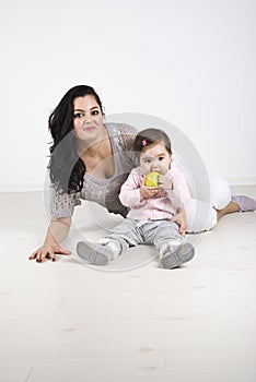 Smiling mother and baby girl sitting on floor