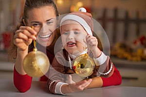 Smiling mother and baby holding christmas balls