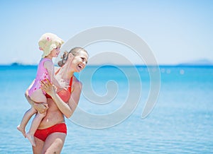 Smiling mother and baby on sea background looking on copy space