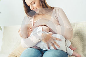 Smiling mother breastfeeding her child in apartment