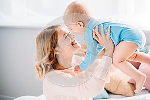 smiling mother carrying happy baby while sitting