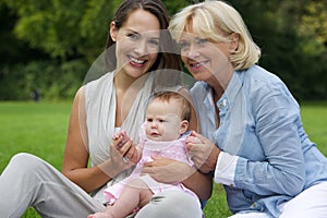 Smiling mother with child and grandmother outdoors