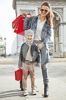 Smiling mother and child with shopping bags in Paris, France