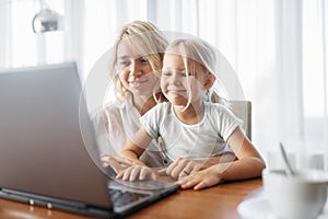 Smiling mother and child uses laptop at home