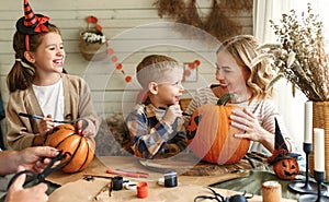 Smiling mother with children creating jack-o-lantern during Halloween celebration at home