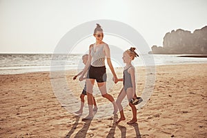 Smiling Mother and children walking together along a sandy beach