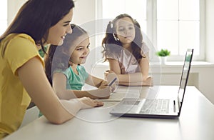 Happy smiling mother and children studying via laptop at home take online class