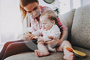 Smiling Mother Combing Hair of Cute Baby Indoors