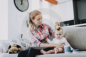 Smiling Mother Combing Hair of Cute Baby Indoors