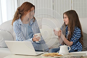 Smiling mother and daughter with laptop at home