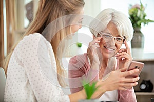 Smiling mother and daughter using cell phone