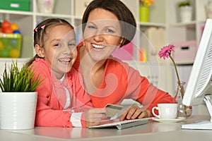 Smiling mother and daughter using computer for online shopping.