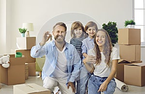 Smiling mother, father and children showing keys to their new house on moving day