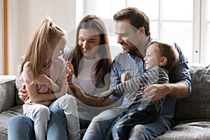 Smiling mother and father having fun with kids on couch