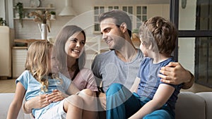 Smiling mother and father with kids sitting on couch