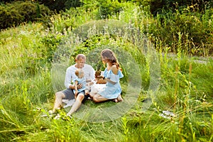 Smiling mother and father with little baby girl enjoy picnic in summer