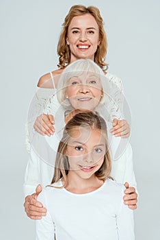 smiling mother, grandmother and granddaughter hugging