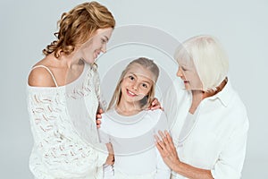 smiling mother, grandmother and granddaughter hugging