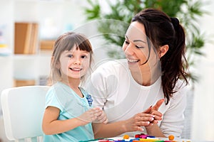 Smiling mother helps a little daughter to sculpt figurines from plasticine. Children`s creativity. Happy family photo