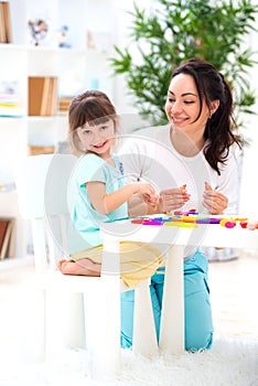 Smiling mother helps a little daughter to sculpt figurines from plasticine. Children`s creativity. Happy family photo