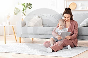 Smiling Mother And Her Adorable Baby Watching Cartoons On Digital Tablet Together