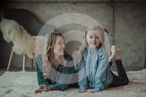 Smiling mother with her daughter in the room on the carpet