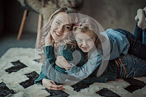 Smiling mother with her daughter in the room on the carpet