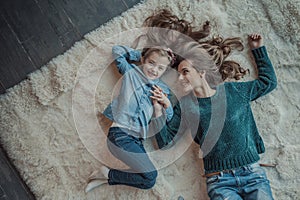 Smiling mother with her daughter in the room on the carpet