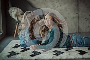 Smiling mother with her daughter in the room on the carpet