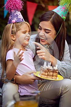 Mother and her girl  celebrate children birthday party and eating cake