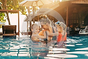 Smiling mother and her two children playing in a pool