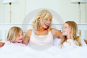 Smiling mother with her two daughter lying in bed. Portrait of a smiling mother with her two daughter lying in bed.