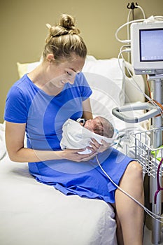 Smiling Mother holding her newborn premature baby in the hospital