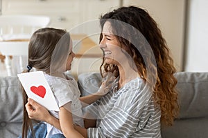 Smiling mother hugging adorable little daughter, thanking for gift