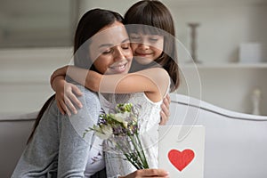 Smiling mother hugging little daughter, thanking for gift and congratulation