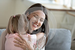 Smiling mother hugging, thanking little daughter for bouquet close up