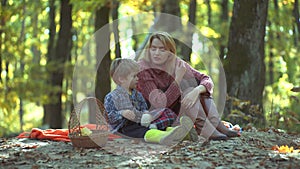 Smiling mother with kid having fun in autumn park. Colorful autumn woman portrait. Young parent and children having