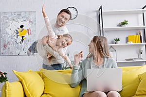 Smiling mother with laptop looking at